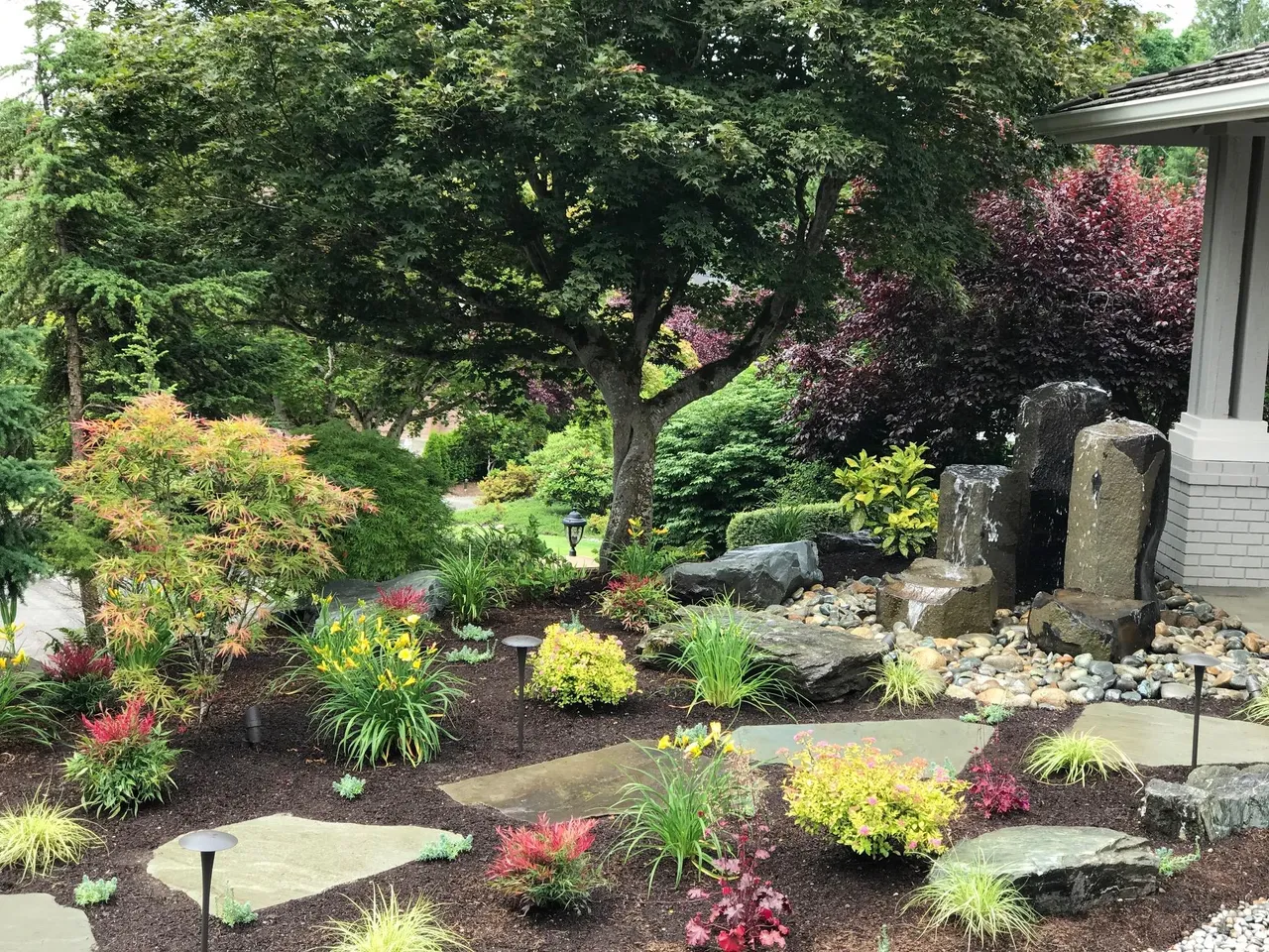 Illuminated water feature with boulder landscaping at dusk